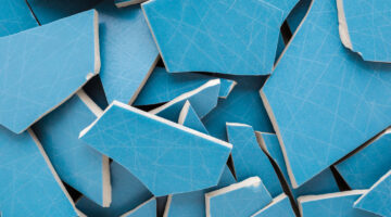 Heap of cracked blue ceramic wall or floor tiles background. Closeup. Top down view.